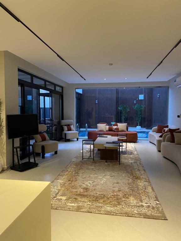 un soggiorno con divani e TV a schermo piatto di شاليه لوسيندا a Baljurashi