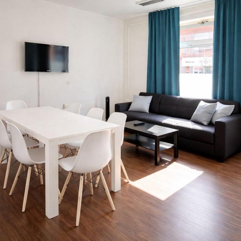 a living room with a white table and a black couch at Worker Place Emmerich in Emmerich