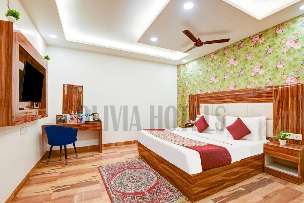 a bedroom with a bed and a desk and a tv at Olivia Hotels - Delhi Airport in New Delhi
