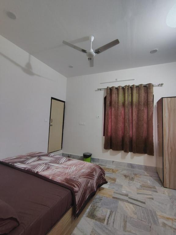 a bedroom with a bed and a ceiling fan at Param Dham in Vrindāvan