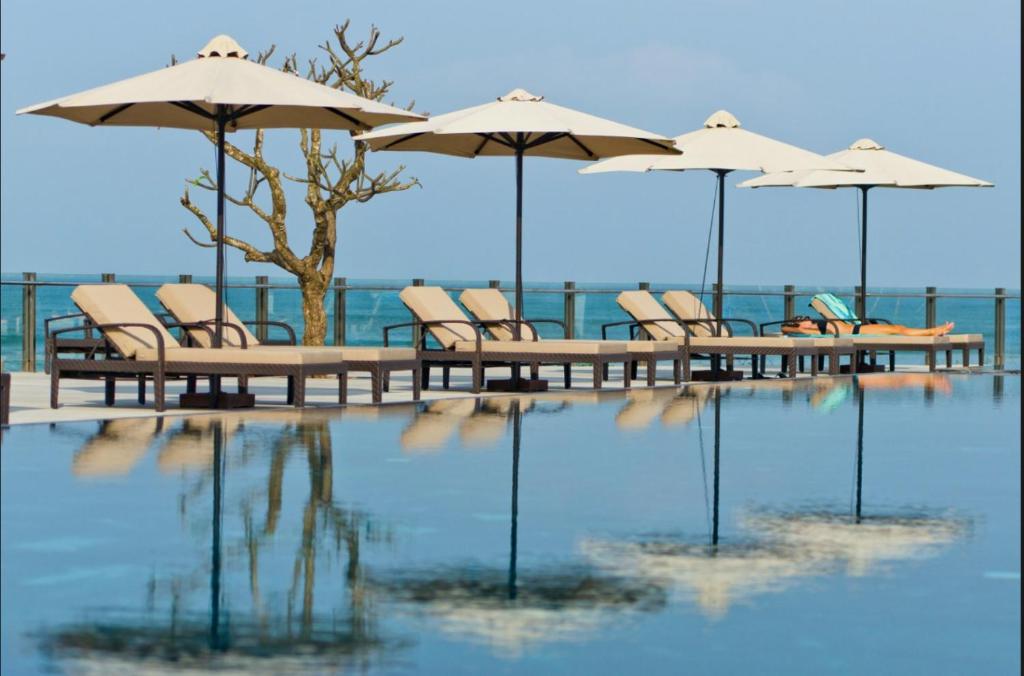 un groupe de chaises et de tables avec parasols et eau dans l'établissement Ocean Apartment, à Đà Nẵng