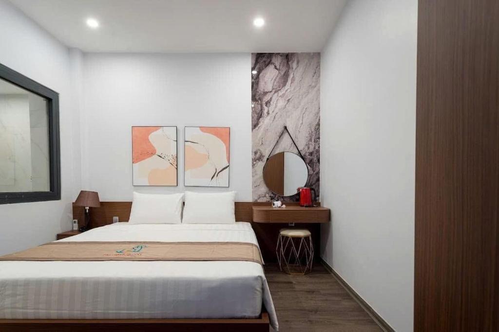 a bedroom with a large bed and a mirror at Kapás Hotel in Hai Phong