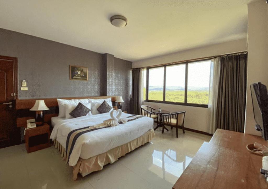 a bedroom with a large bed and a large window at Sirimathani Hotel in Ban Hua Fai