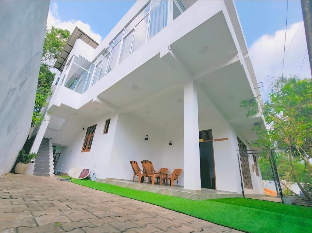 an exterior view of a white house with chairs at Relax inn modara in Mirissa