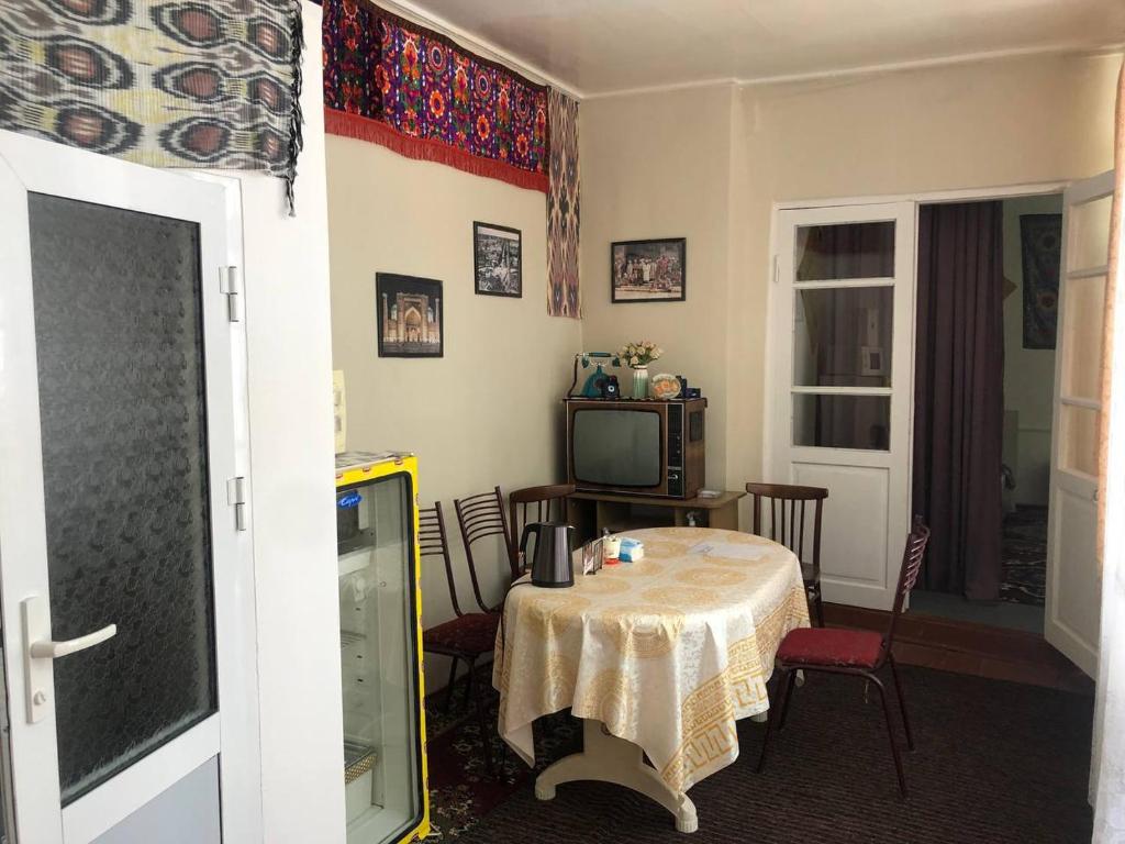 een kamer met een tafel met stoelen en een televisie bij Javoxir Guest House in Samarkand