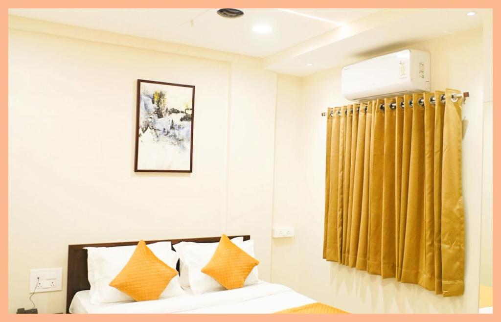 1 dormitorio con cama y cortina amarilla en The Residency Inn Visawa Kolhapur, en Kolhapur