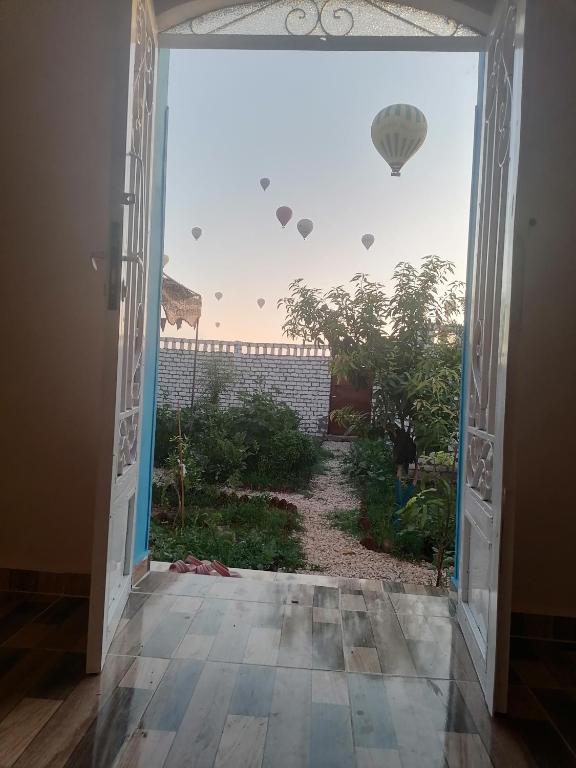 an open door with a view of a garden and hot air balloons at Osama House Luxor in Al Qurnah