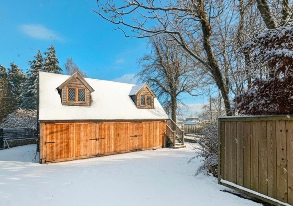 Edinburgh's Winter Chalet في روزلين: حظيرة خشبية في الثلج مع سياج
