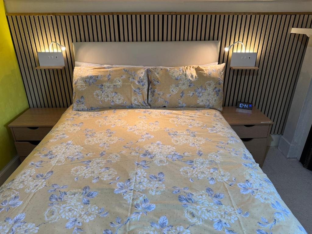 Una cama en un dormitorio con dos mesitas de noche y una colcha con azul. en Harbour House Bed & Breakfast - Wick, en Wick