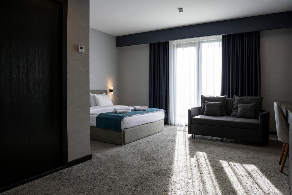 a bedroom with a bed and a couch and a window at The West Inn-Georgia Hotel in Kutaisi