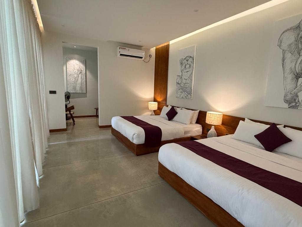 a hotel room with two beds and a desk at Four Chalets Yala in Tissamaharama