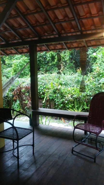 two chairs on a porch with a view of trees at Boipeba Apartamento GREEN com varanda e cozinha ao ar livre in Cayru