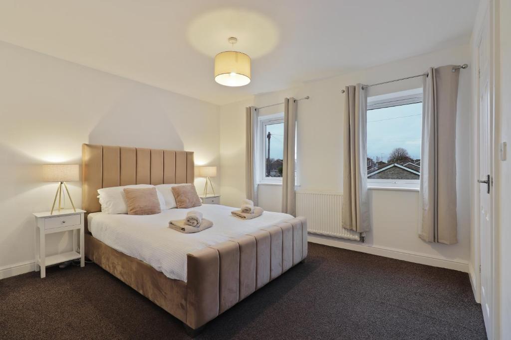 a bedroom with a large bed and two windows at Spacious 3 Bed - FREE Parking - Great for Workers in Conisbrough