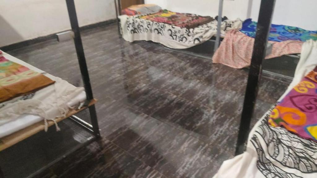 a room with three bunk beds and a wooden floor at Cpdretreathostel in Arambol