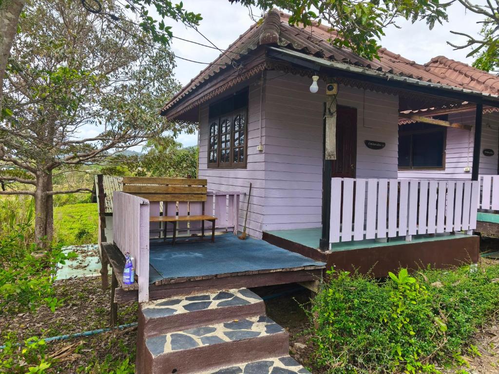 a small white house with a bench on the porch at เขาค้อ ภูดาว Resort & Camping in Khao Kho