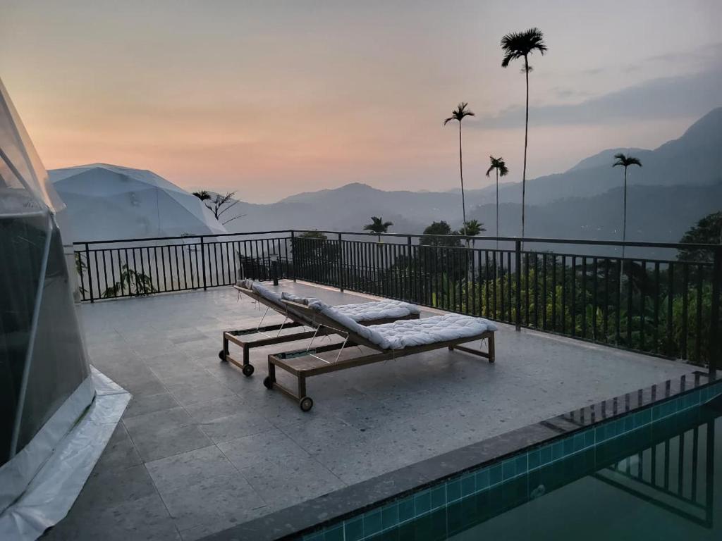 a pool with two chaise lounges next to at Astara Munnar in Munnar