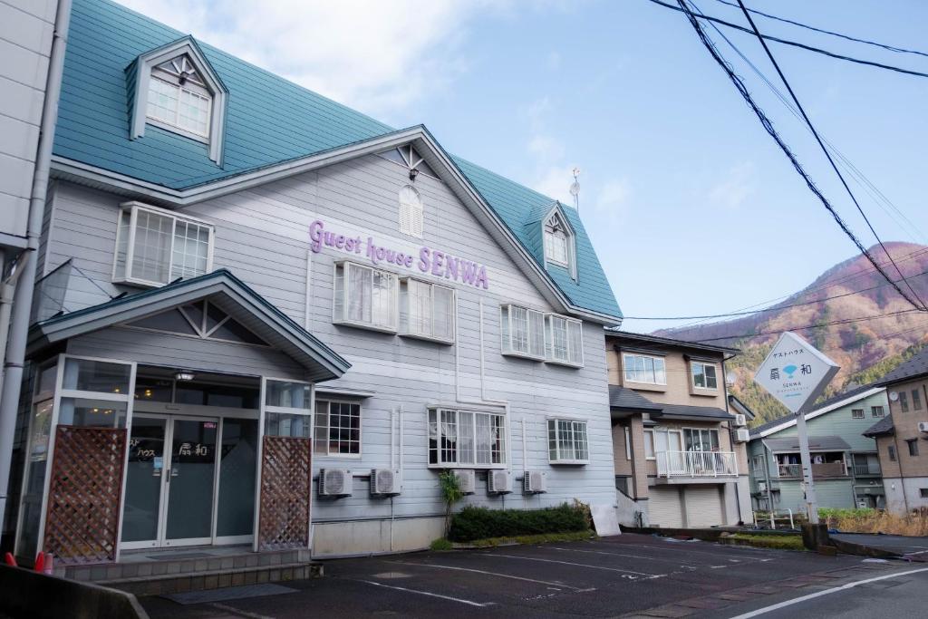 a white building with a purple sign on it at Guest house SENWA in Yuzawa