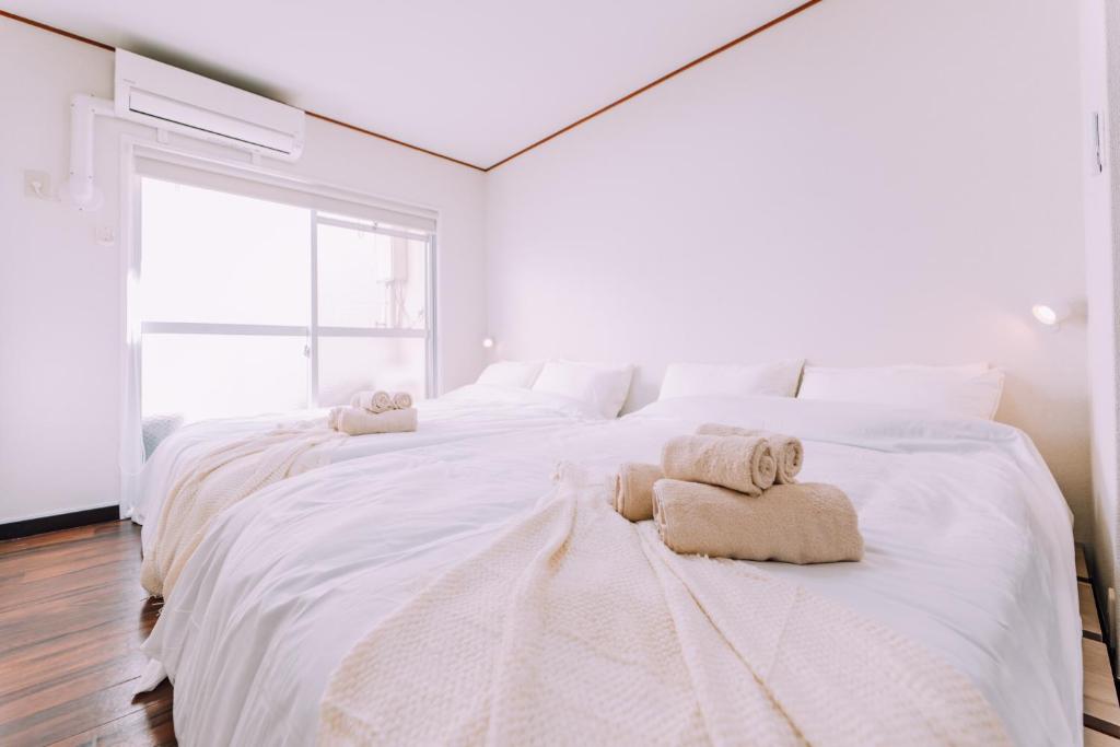 Un dormitorio con una gran cama blanca con toallas. en Fukuoka Hakata Stay 1BR with Balcony, TV and Laundry 206, en Wada