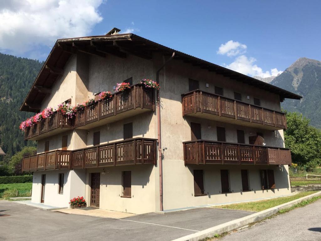 - un bâtiment avec des balcons en bois et des fleurs dans l'établissement Pinzolocasa, à Pinzolo