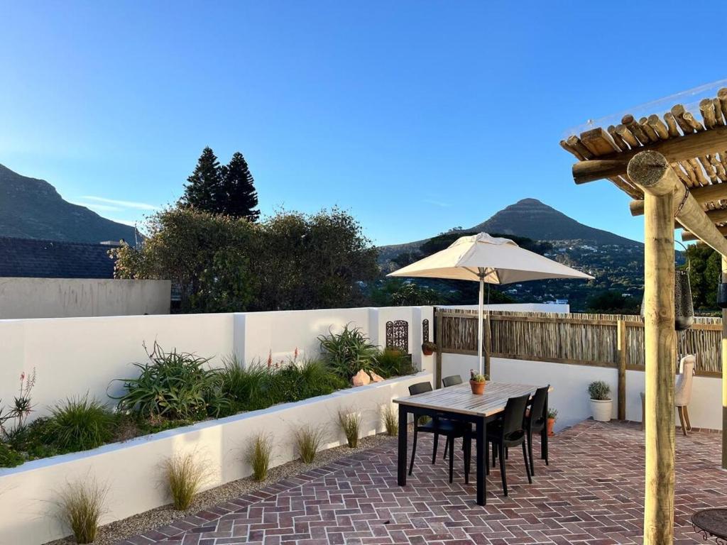 a patio with an umbrella and a table and chairs at Ibis Cottage Hout Bay with Mountain View Terrace in Hout Bay