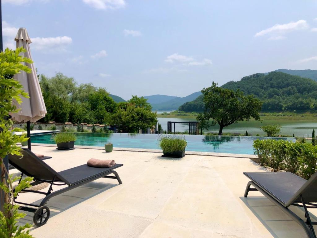 Drive Point (Adventure Lake Resort) في Asparukhovo: مسبح مع كرسيين للصالة ومظلة