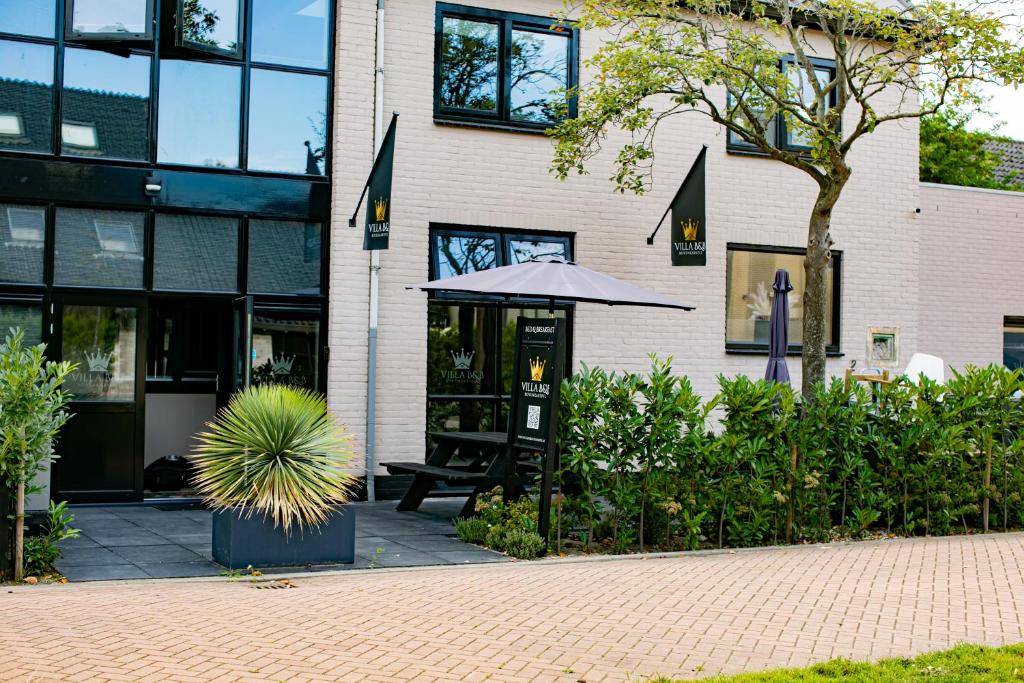a building with a table and an umbrella in front of it at Villa B&B Bovenkarspel in Bovenkarspel