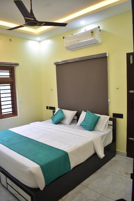 Un dormitorio con una cama grande con almohadas verdes y blancas. en De Waves, en Varkala