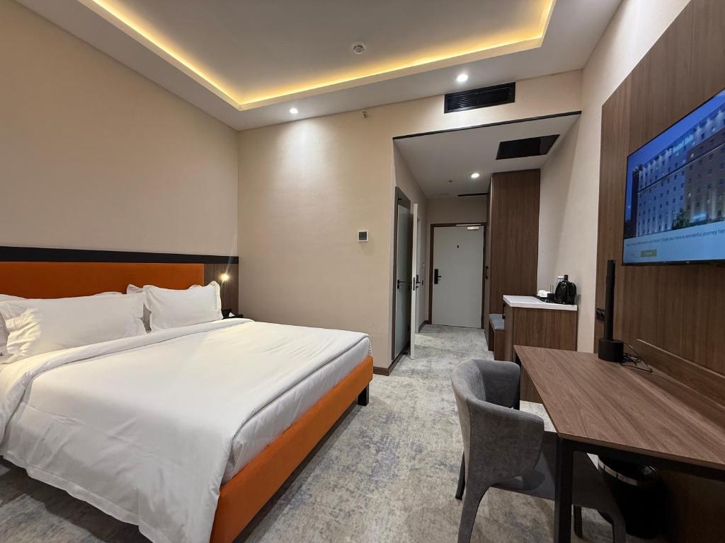 a bedroom with a bed and a desk and a tv at Afrosiyob in Stantsiya Kyzyl-Tukumachi