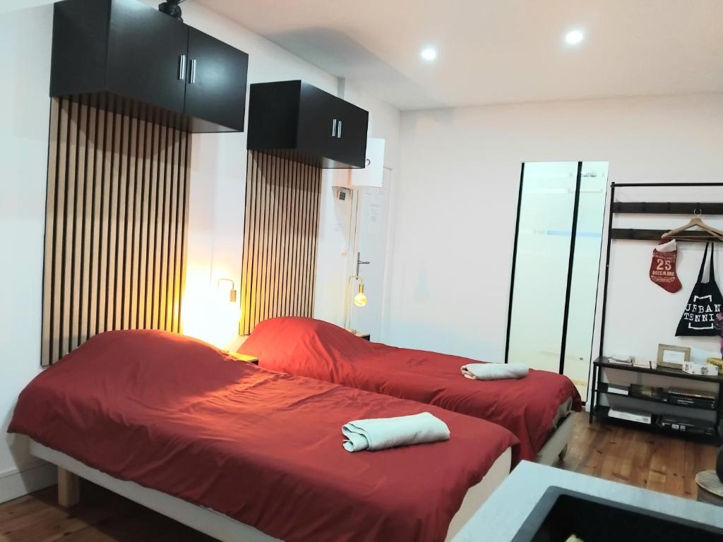 Appartement Parking Wifi Terrasse cosy في Condé-sur-Sarthe: سريرين مع شراشف حمراء في الغرفة