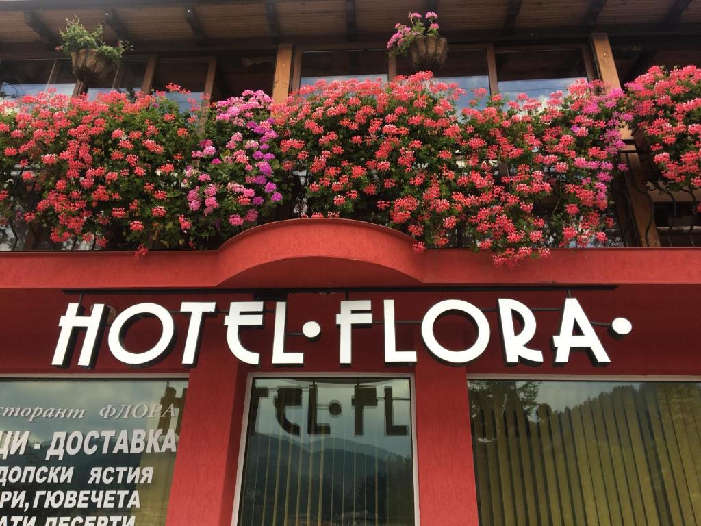 a sign for a hotel floria with flowers in a window at Семеен Хотел Флора in Zlatograd
