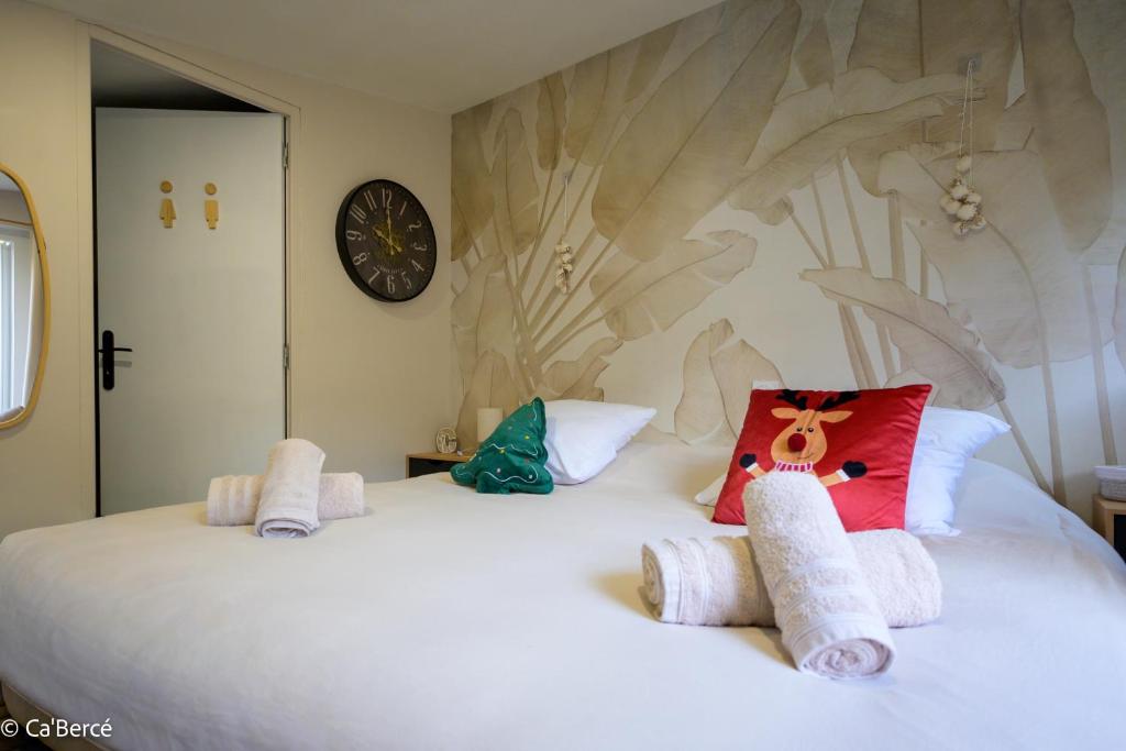 a bedroom with a large white bed with a clock on the wall at Ca'Bercé Studio équipé in Château-du-Loir