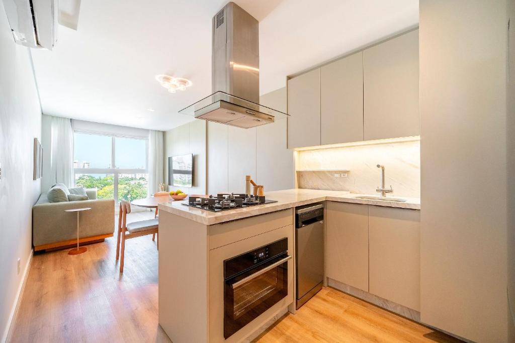 eine Küche mit weißen Schränken und einem Herd mit Backofen in der Unterkunft Rivieira 2 Suítes e Jacuzzi by Achei Camboriu in Cabeçudas