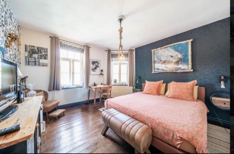 een slaapkamer met een groot bed en een bureau bij L'Ancienne Boulangerie in Durbuy