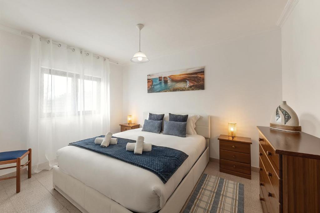 a bedroom with a large white bed with blue pillows at Ocean Breeze Baleal in Ferrel