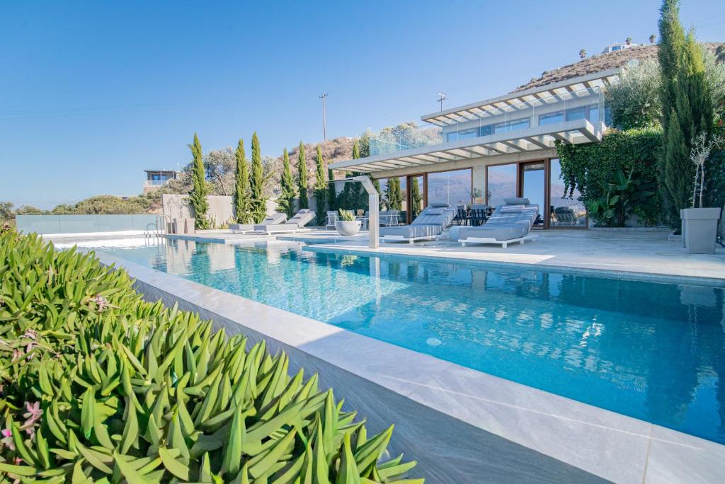 a swimming pool with chairs and a house at Marnos Luxury Villas in Kamilari