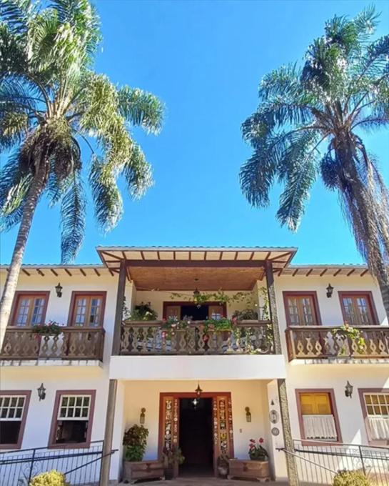 un edificio con balcón y 2 palmeras en Pousada da Serrinha, en Mariana