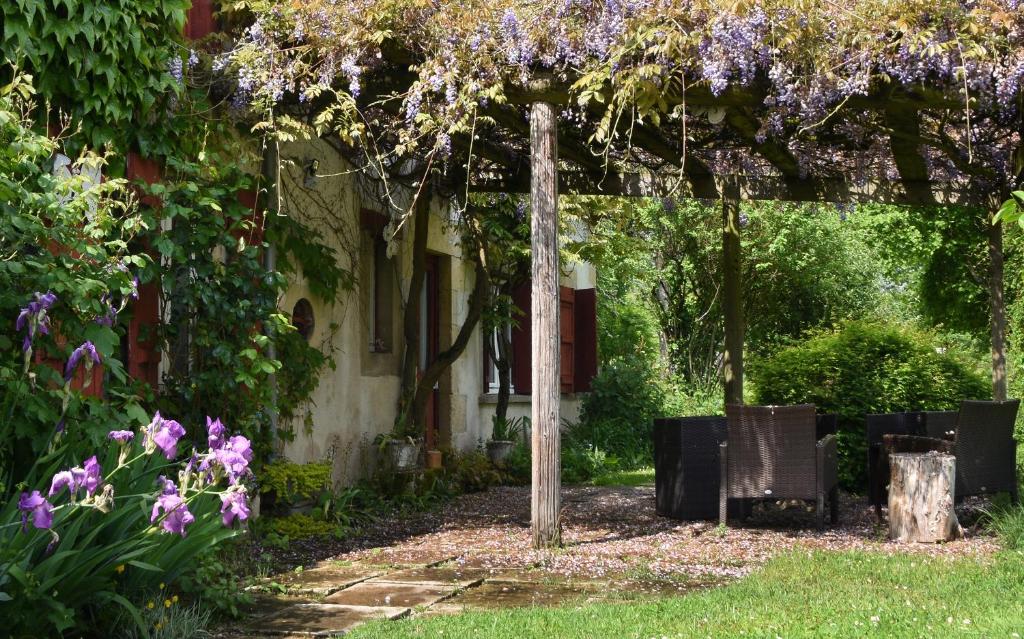 a garden with a pergola with purple flowers at La Longère du Sallay in Saincaize-Meauce