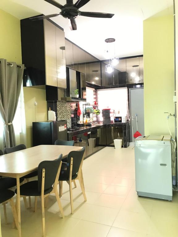 a kitchen with a wooden table and chairs and a dining room at Fidaiy Homestay in Teronoh