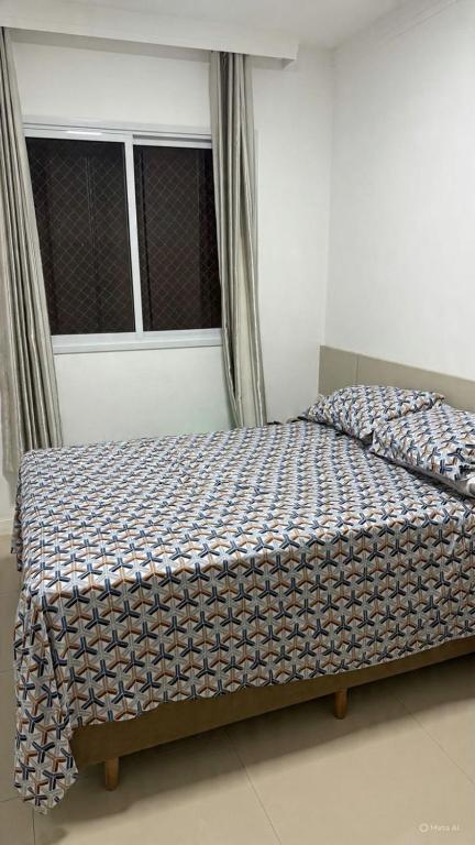 Apto 2 dormitórios Itapema في ايتابيما: سرير مع لحاف في غرفة النوم