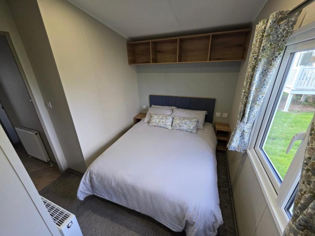 een kleine slaapkamer met een bed en een raam bij Luxury 3 bed sleeps 8 caravan with sea view in Exmouth
