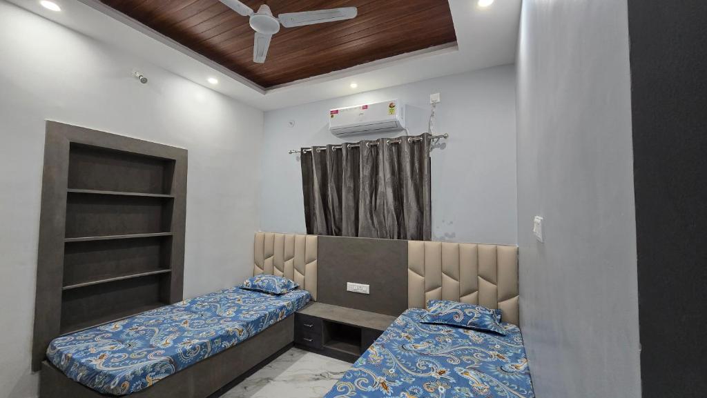 ein Schlafzimmer mit zwei Betten und einem Deckenventilator in der Unterkunft Deoghar BnB in Deoghar