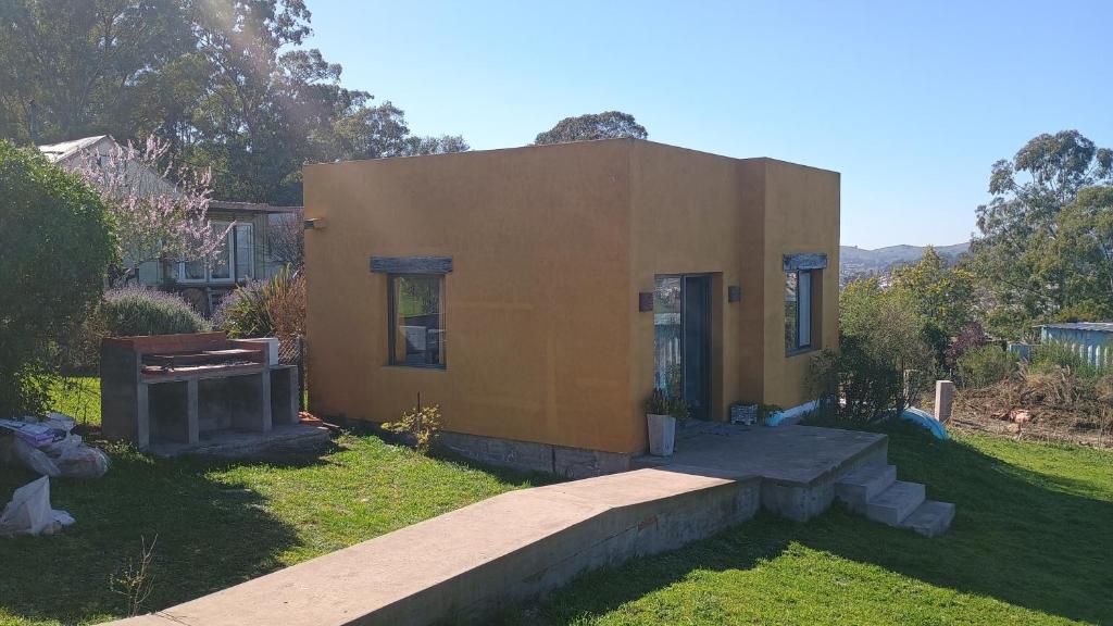Una pequeña casa en un patio con una pasarela. en Cabaña La Resolana, en Tandil