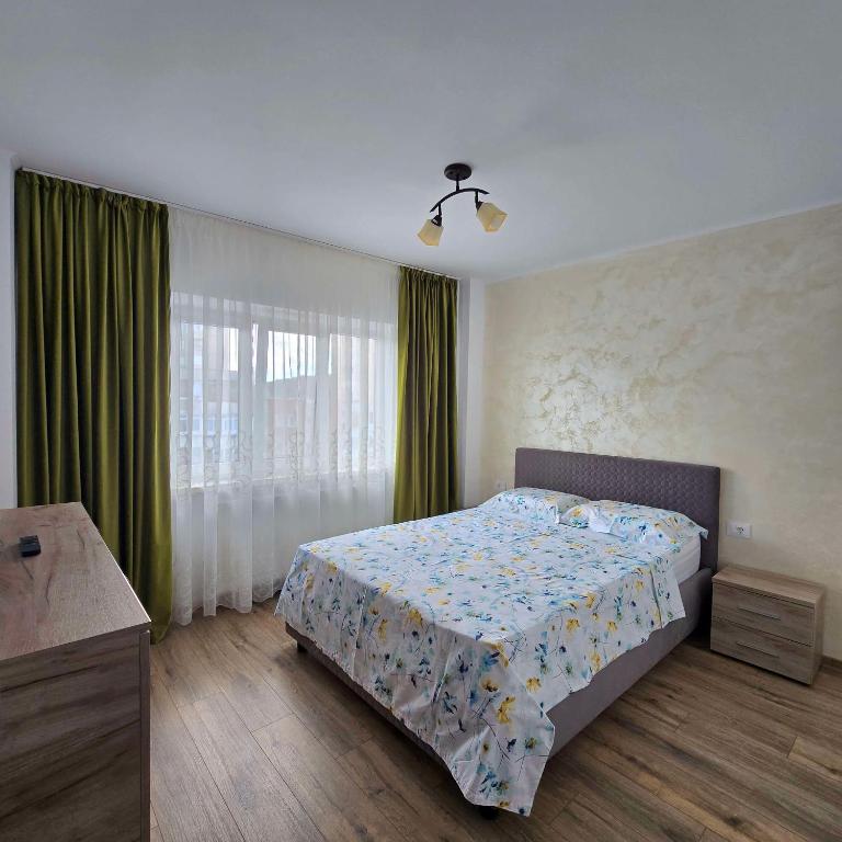 a bedroom with a bed and a window with green curtains at Downtown City Apartment in Râmnicu Vâlcea