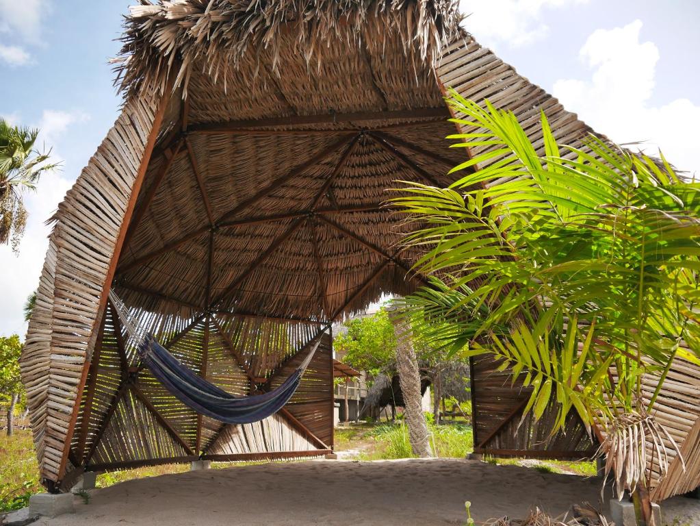 un hamac dans une hutte de paille avec un palmier dans l'établissement Chalé na Lagoa, à Guriú