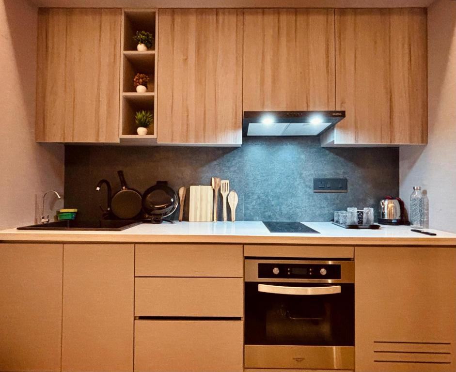 een keuken met houten kasten en een kookplaat met oven bij Vaelora Stay - Skyline Studio with glass wall in Ghaziabad