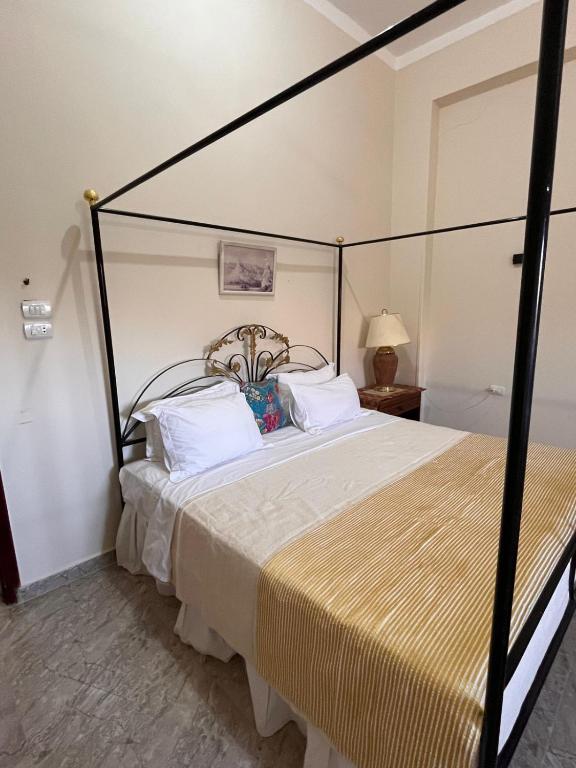 a bedroom with a black canopy bed with white pillows at Abdalla's House in Al Aqālitah