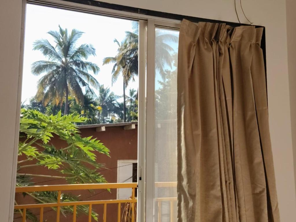uma janela com vista para uma palmeira em Hare Krishna Beach Resort em Srīvardhan