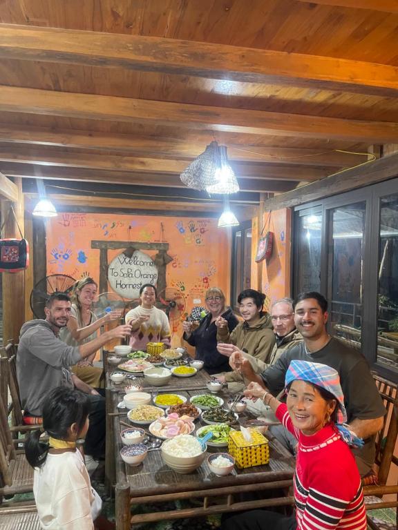 un grupo de personas sentadas alrededor de una mesa con comida en Sapa Orange Homestay, en Sa Pa