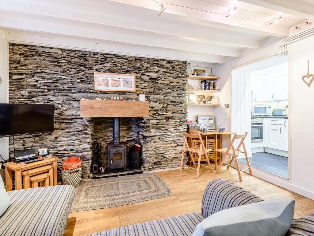 een woonkamer met een stenen muur en een open haard bij Pebble Cottage - Uk32243 in Aberdyfi