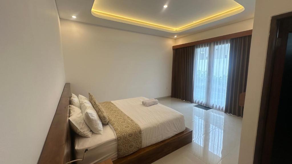 een slaapkamer met een bed en een groot raam bij Honeymoon Villa canggu in Sempidi